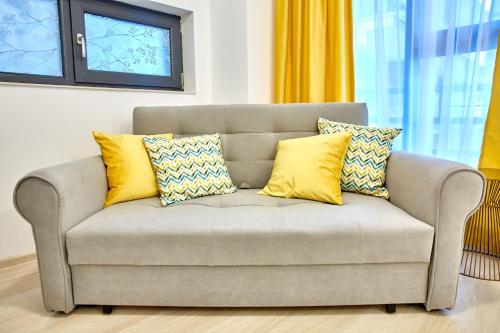 ein Sofa mit gelben Kissen auf einem Zimmer in der Unterkunft Golden Studio in Mamaia Nord – Năvodari