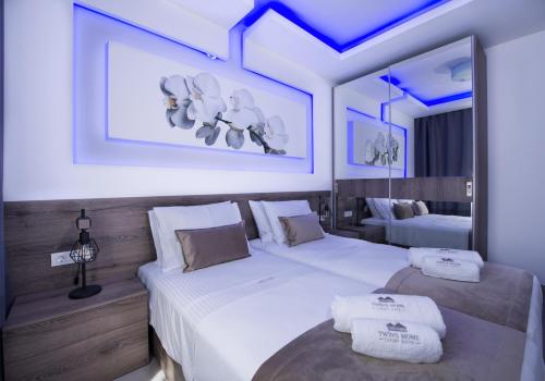 una camera d'albergo con due letti con lenzuola bianche di TWIN'S HOME LUXURY SUITES a Alikianós