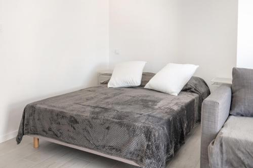 1 cama con 2 almohadas junto a un sofá en L'Oasis, en Palavas-les-Flots