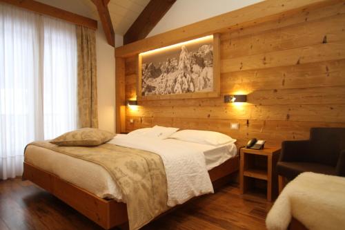 a hotel room with a bed and a chair at Hotel La Bussola in Andalo