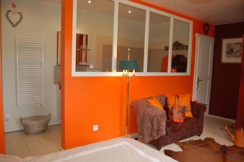 uma sala de estar com paredes cor de laranja e um sofá em Un Air de Campagne em Couloisy