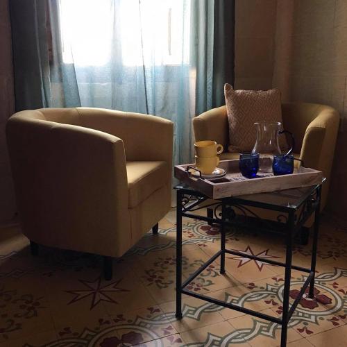 a living room with two chairs and a coffee table at Ta Marie Merhba in Żebbuġ