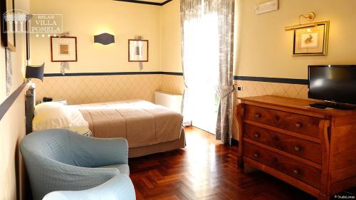 a bedroom with a bed and a tv and a chair at Relais Villa Pomela in Novi Ligure