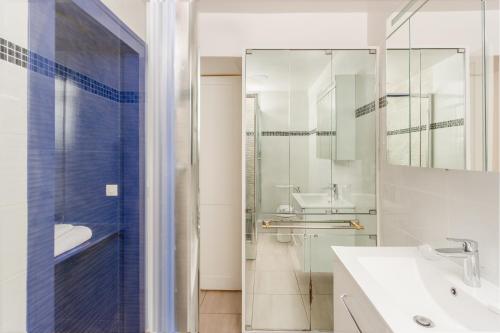 une salle de bain avec une douche en verre et un lavabo dans l'établissement Saint Honore Louvre with AC, à Paris