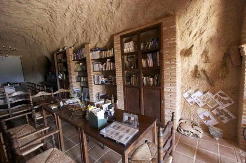 Habitación con mesa y estanterías en Hábitat Troglodita Almagruz, en Purullena
