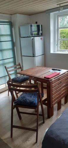 a kitchen with a wooden table and two chairs at Cozy tiny room, mini kitchen and bathroom in Otterup