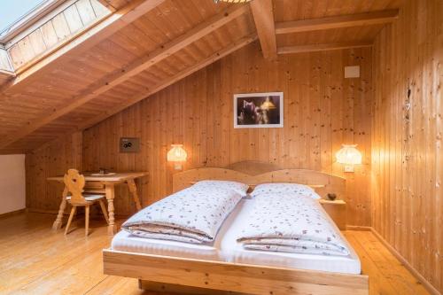 1 dormitorio con 1 cama en una pared de madera en Ferienwohnung Aster Nusserhof, en Avelengo