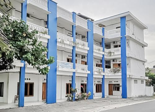 a large white building with blue columns at RedDoorz Syariah near Sunrise Park Pangandaran in Pangandaran