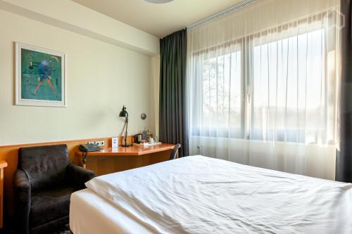 ein Hotelzimmer mit einem Bett, einem Stuhl und einem Fenster in der Unterkunft DOBLERGREEN Hotel Stuttgart-Gerlingen in Gerlingen