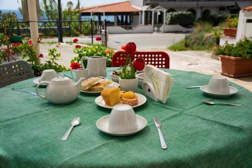 a green table with plates of food and cups and spoons at La Meriggia B&B in Pisciotta