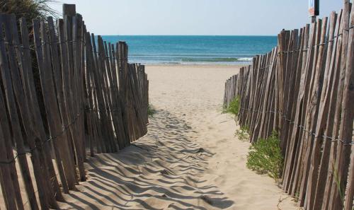 a fence on a beach with the ocean in the background at Appartement REZ DE JARDIN avec SPA entre la MER et Montpellier 10mn in Lattes