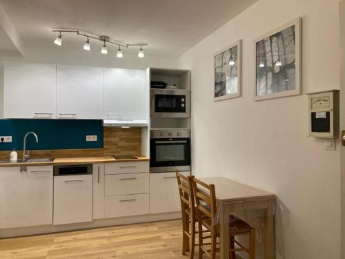 une cuisine avec des armoires blanches et une table en bois dans l'établissement Appartement Les Amethystes 1, à Le Mont-Dore