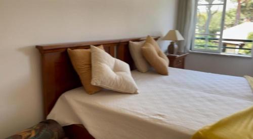 Un dormitorio con una cama con almohadas y una ventana. en Praia da Falésia Alfa Mar Albufeira, en Olhos de Água