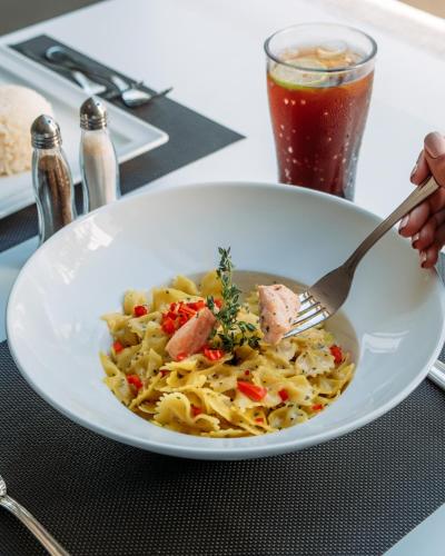 a bowl of pasta with meat and vegetables with a fork at Palma Hotel in Port Said