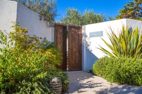 a wooden door in a white building with plants at Hôtel Cala di Greco in Bonifacio