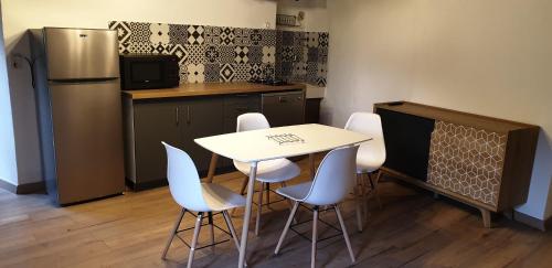 une cuisine avec une table, des chaises et un réfrigérateur dans l'établissement Appartement de charme vieille ville, à Corte