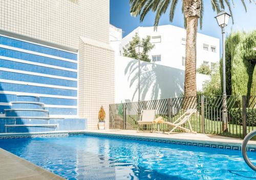 a swimming pool with a palm tree and a building at Parador de Mérida in Merida