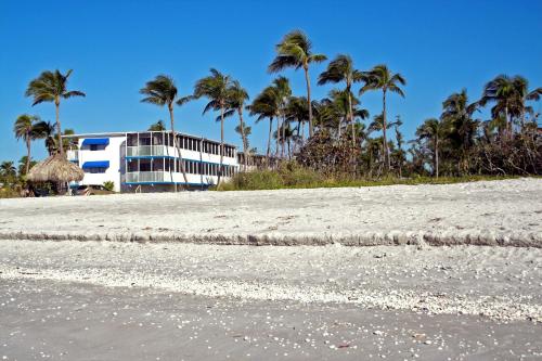 a building on the beach with palm trees in the background at Sunset Beach Inn in Sanibel