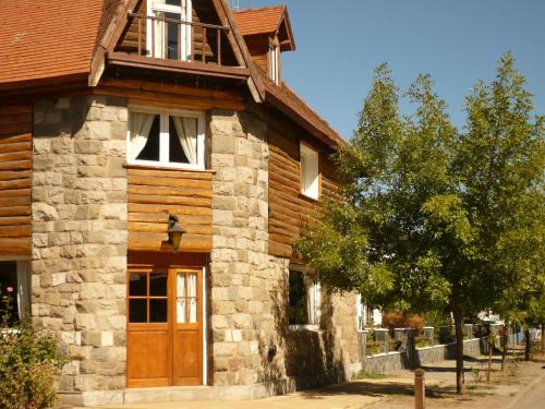 una casa in pietra con una porta in legno e un albero di Hotel Turismo a San Martín de los Andes