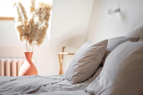 a bed with pillows and a vase with a plant at Nidos Banga in Nida