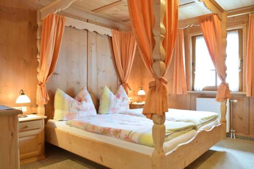 a bedroom with a canopy bed with orange curtains at Landhaus Huber in Elbigenalp