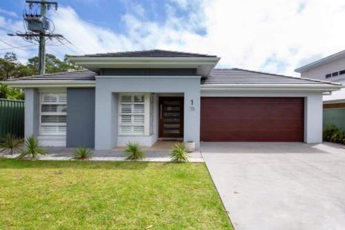 a small house with a red garage at Callala Bay Beach House - Wowly Waters - Pet Friendly in Callala Bay