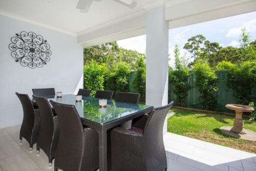 an outdoor dining room with a glass table and chairs at Callala Bay Beach House - Wowly Waters - Pet Friendly in Callala Bay