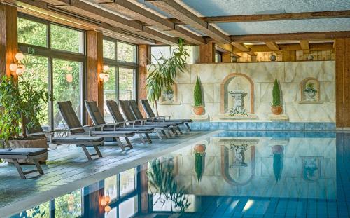 a swimming pool with lounge chairs and a swimming pool at Ringhotel Mönch`s Waldhotel in Unterreichenbach
