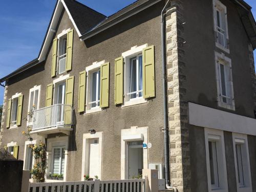 a brick house with yellow shutters on it at La Chtite Maison Béarnaise in Arthez-de-Béarn