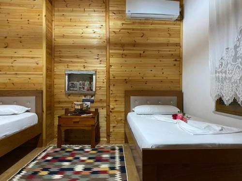 two beds in a room with wooden walls at Ahmetaj Guest House in Gjirokastër