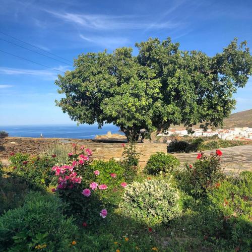 a tree in the middle of a field with flowers at Harma Villas in Andros