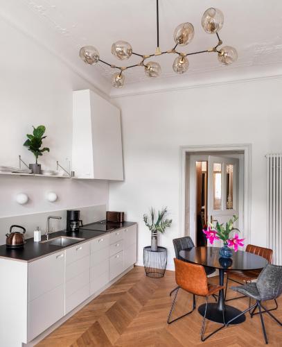 a kitchen with white cabinets and a table with chairs at MN6 Luxury Suites by Adrez in Prague