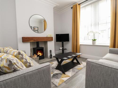 a living room with a fireplace and a mirror at Acorn Cottage in Skipton