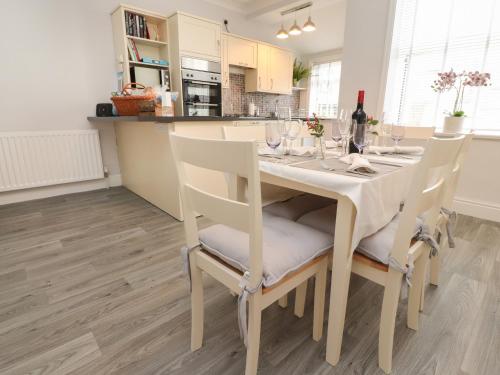 a dining room table with white chairs and a kitchen at Acorn Cottage in Skipton
