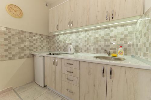 a kitchen with a sink and a clock on the wall at Apartments Vjera Petrovac in Petrovac na Moru