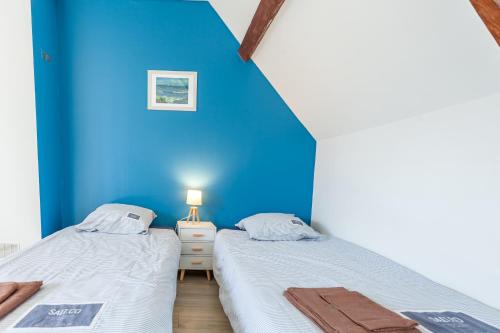 Dos camas en una habitación con una pared azul. en Holiday Normandy se ressourcer à deux pas de la Mer, en Fermanville