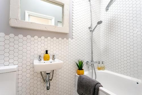 The Bs Hive, Modern, stylish, 2 bedroom house, in Harrogate centre في هاروغايت: حمام أبيض مع حوض وحوض استحمام
