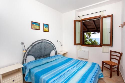 Un dormitorio con una cama y una ventana y una silla. en Casa sulla spiaggia 1, en Orosei