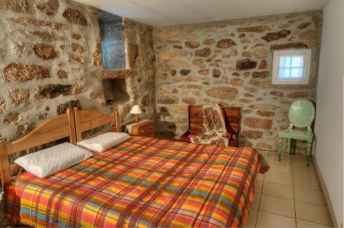 ein Schlafzimmer mit einem Bett und einer Steinmauer in der Unterkunft Casa Entre as Serras in Antigo de Arcos