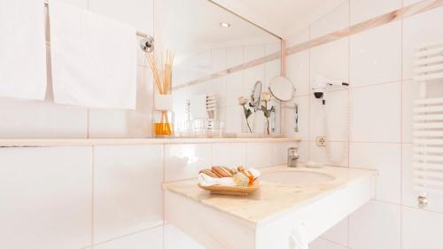 a white bathroom with a sink and a mirror at Superior Hotel Tirolerhof - Zell am See in Zell am See