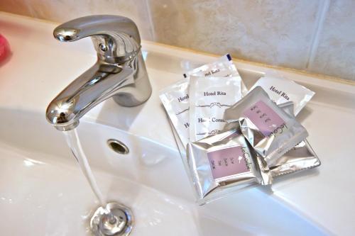 a bathroom sink with a faucet and complimentary soap at Hotel Rita in Riccione