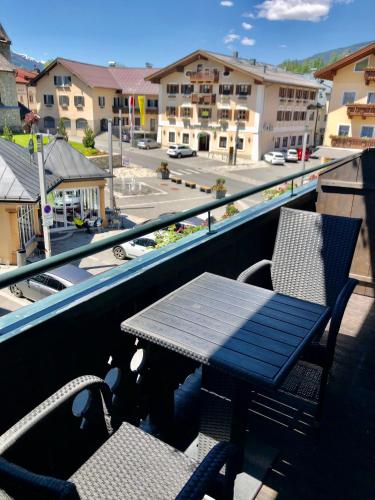 a table and chairs on a balcony with a view of a city at Haus Maria in Bruck an der Großglocknerstraße