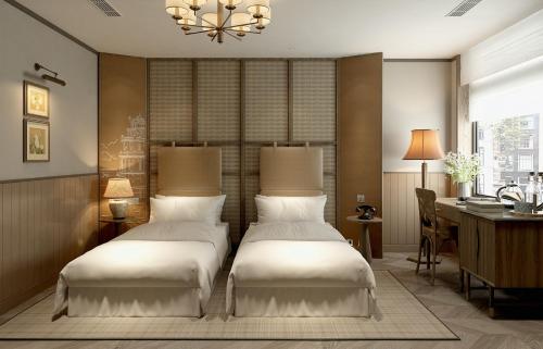 two beds in a hotel room with a desk and a desk at La Passion Hanoi Hotel & Spa in Hanoi