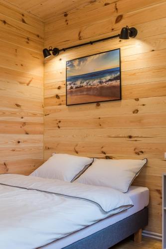 a bedroom with wooden walls and a bed with white pillows at Domki u Moni in Karwieńskie Błoto Pierwsze