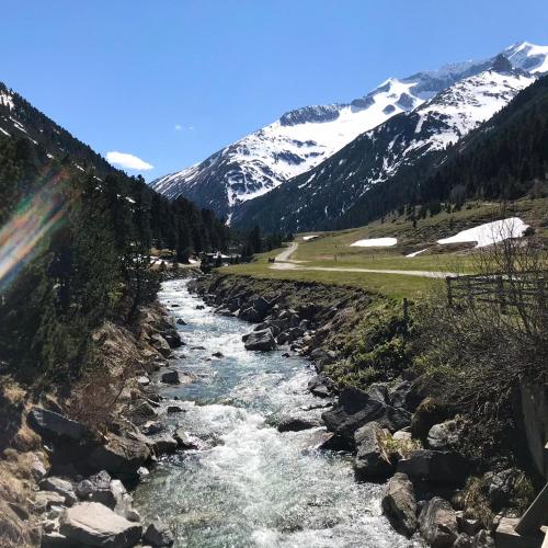 a river with snow capped mountains in the background at Mountain Penthouse Top 8 & 9 in Fügen