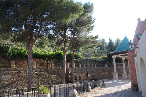 a stone wall with trees next to a building at EL CASTELLET in Traiguera