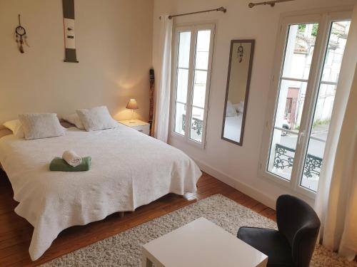 a bedroom with a white bed and two windows at Maison de ville confortable avec cour interieure in Angoulême