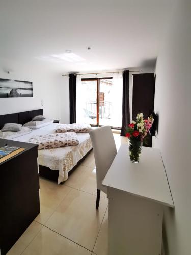 a room with two beds and a table with a vase of flowers at Pansion Makina in Vodice