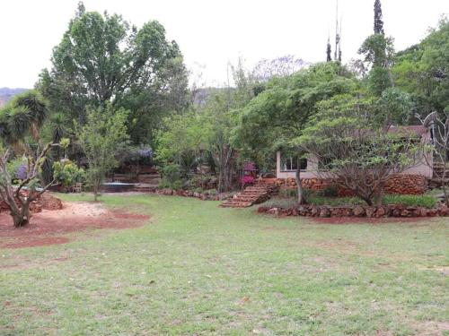 a yard with trees and grass and a house at Goederus Guest Farm in Sterkspruit
