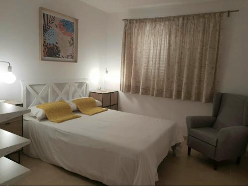 a bedroom with a white bed and a chair at Tabaiba in Costa Calma